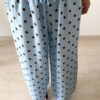 Femme portant un pantalon bleu ciel à pois marron avec taille élastique et lien de serrage, associé à un haut uni.