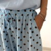 Femme portant un pantalon bleu ciel à pois marron avec taille élastique et lien de serrage, associé à un haut uni.
