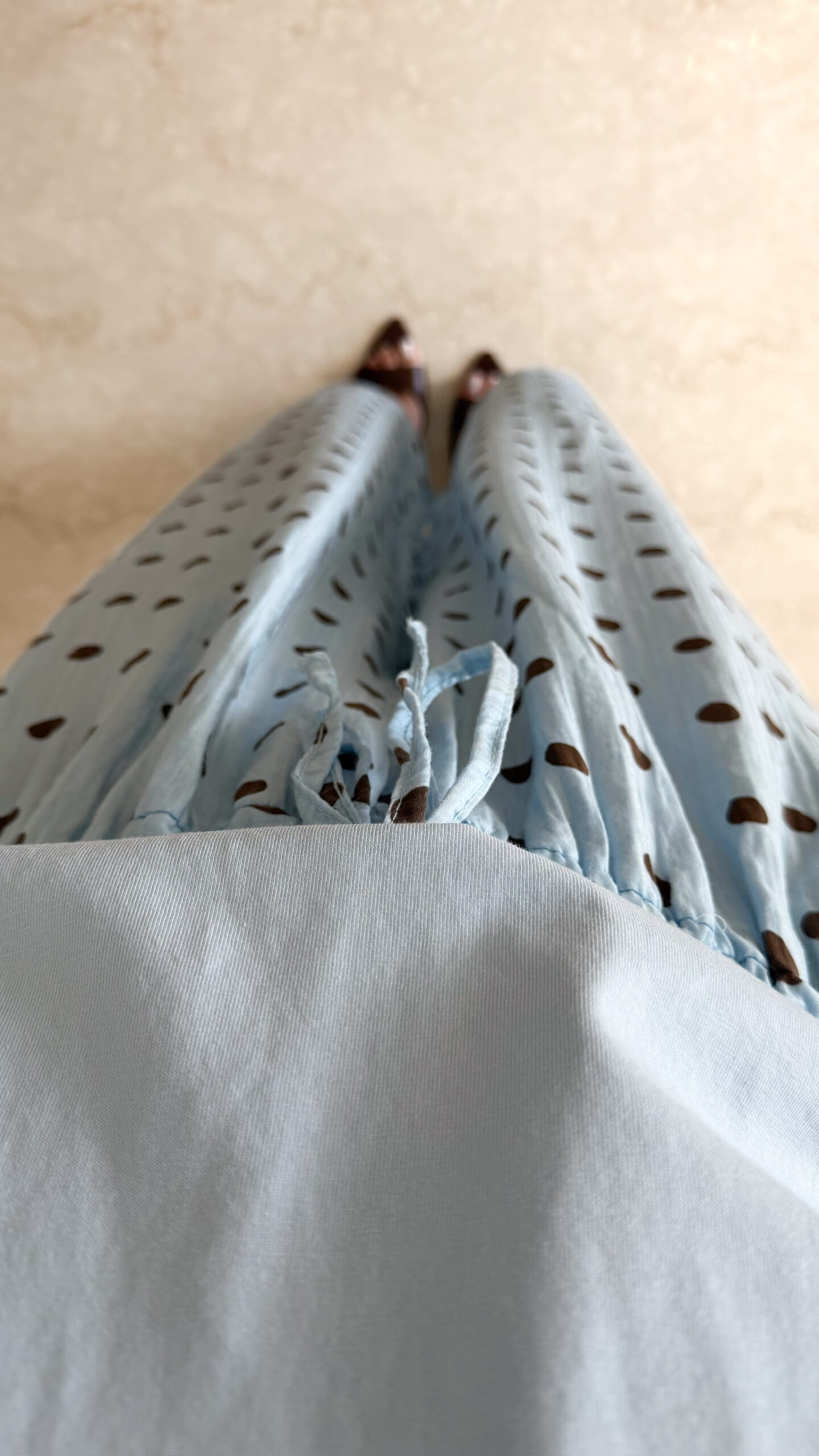 Femme portant un pantalon bleu ciel à pois marron avec taille élastique et lien de serrage, associé à un haut uni.