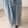 Femme portant un pantalon bleu ciel à pois marron avec taille élastique et lien de serrage, associé à un haut uni.