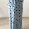 Femme portant un pantalon bleu ciel à pois marron avec taille élastique et lien de serrage, associé à un haut uni.