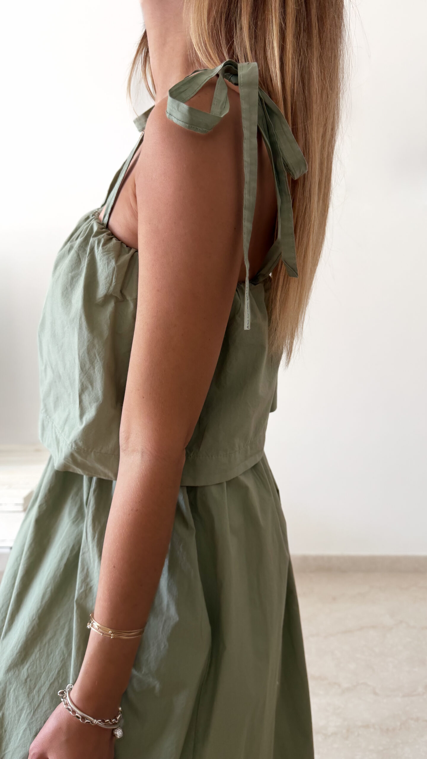 Robe midi kaki pour femme à bretelles nouées, coupe ample et fluide avec poches, style bohème chic et décontracté.