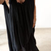 Robe longue noire à fines bretelles pour femme, coupe ample et fluide avec détails pompons, style bohème chic.