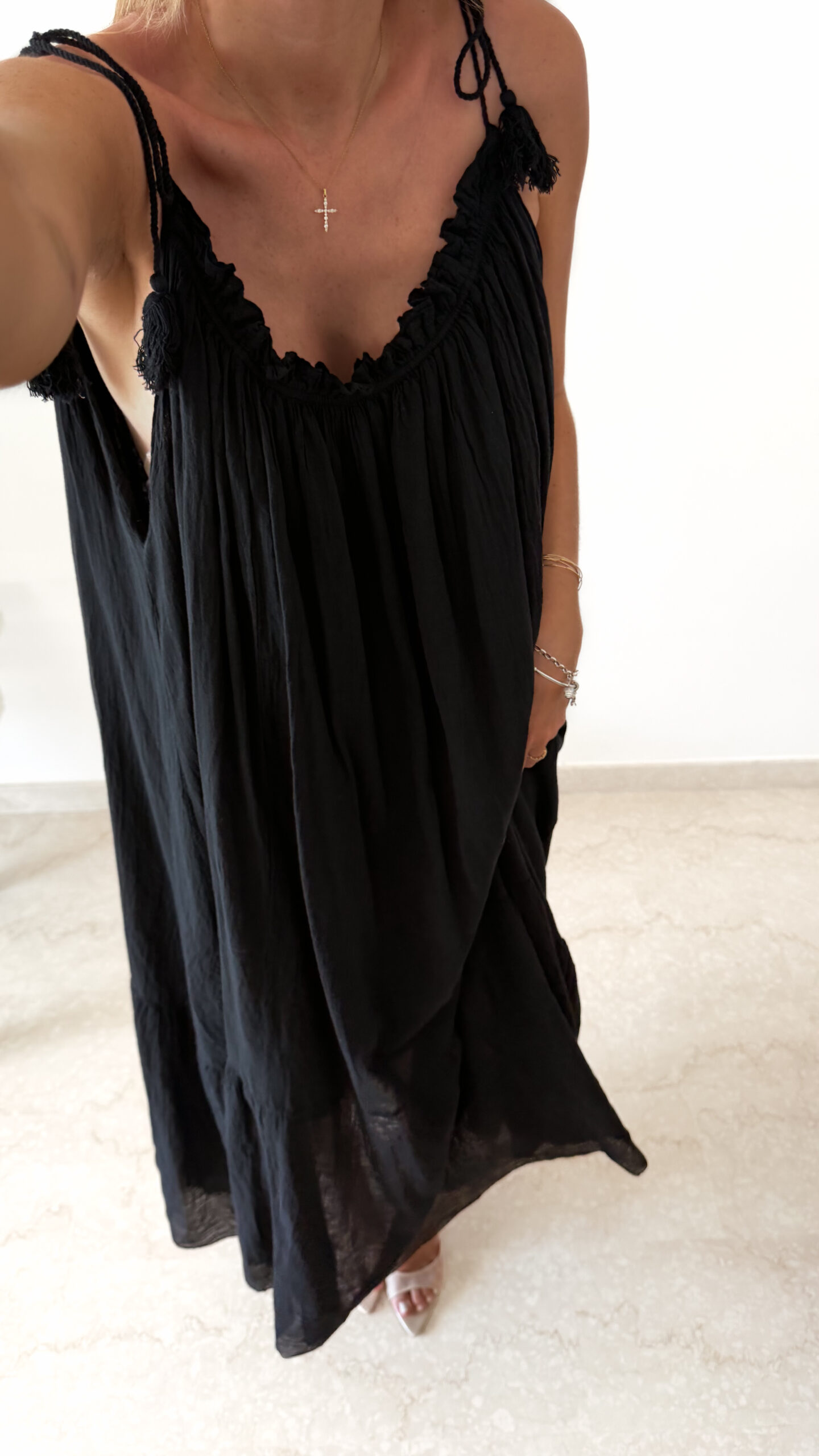 Robe longue noire à fines bretelles pour femme, coupe ample et fluide avec détails pompons, style bohème chic.