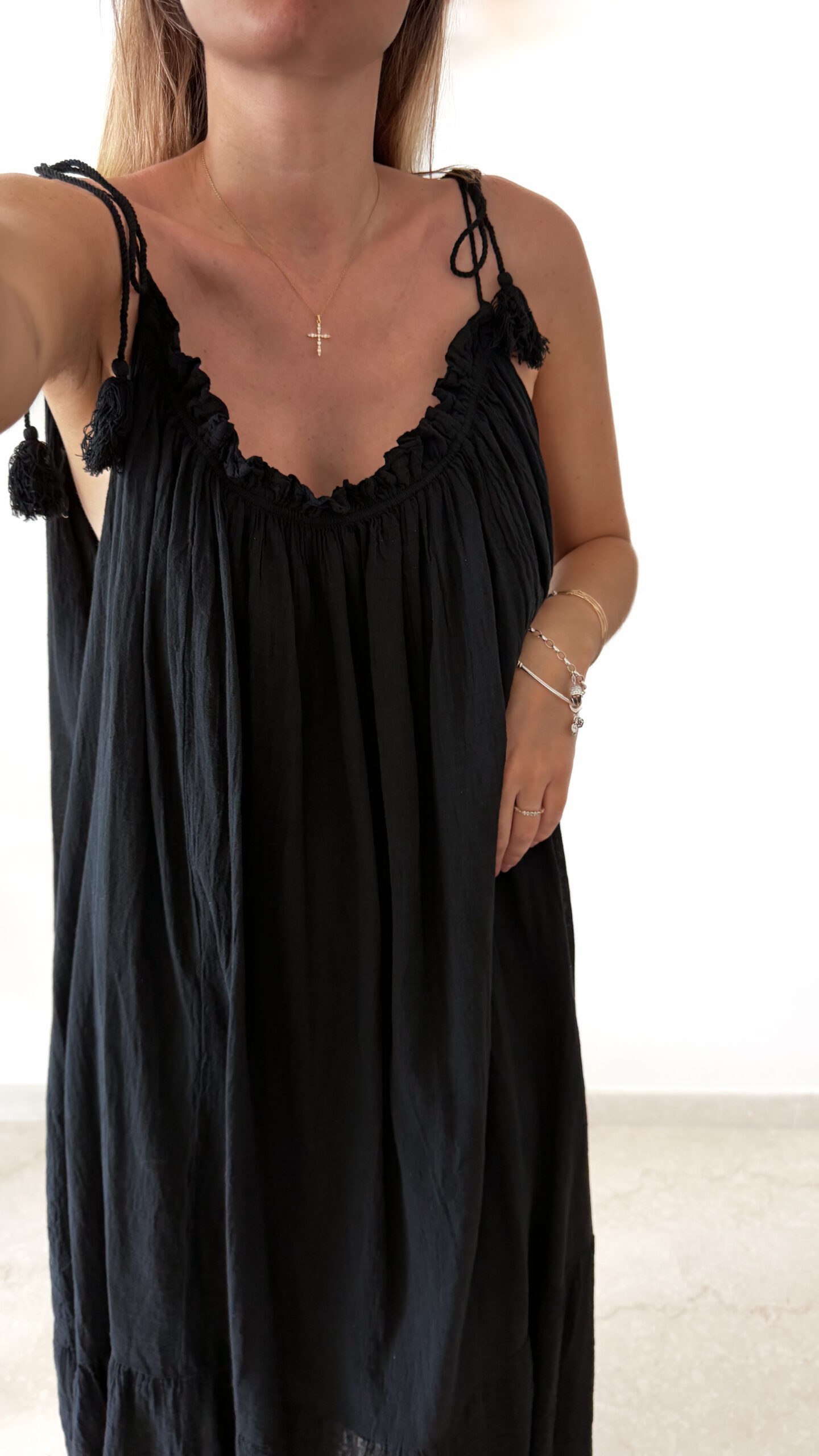 Robe longue noire à fines bretelles pour femme, coupe ample et fluide avec détails pompons, style bohème chic.