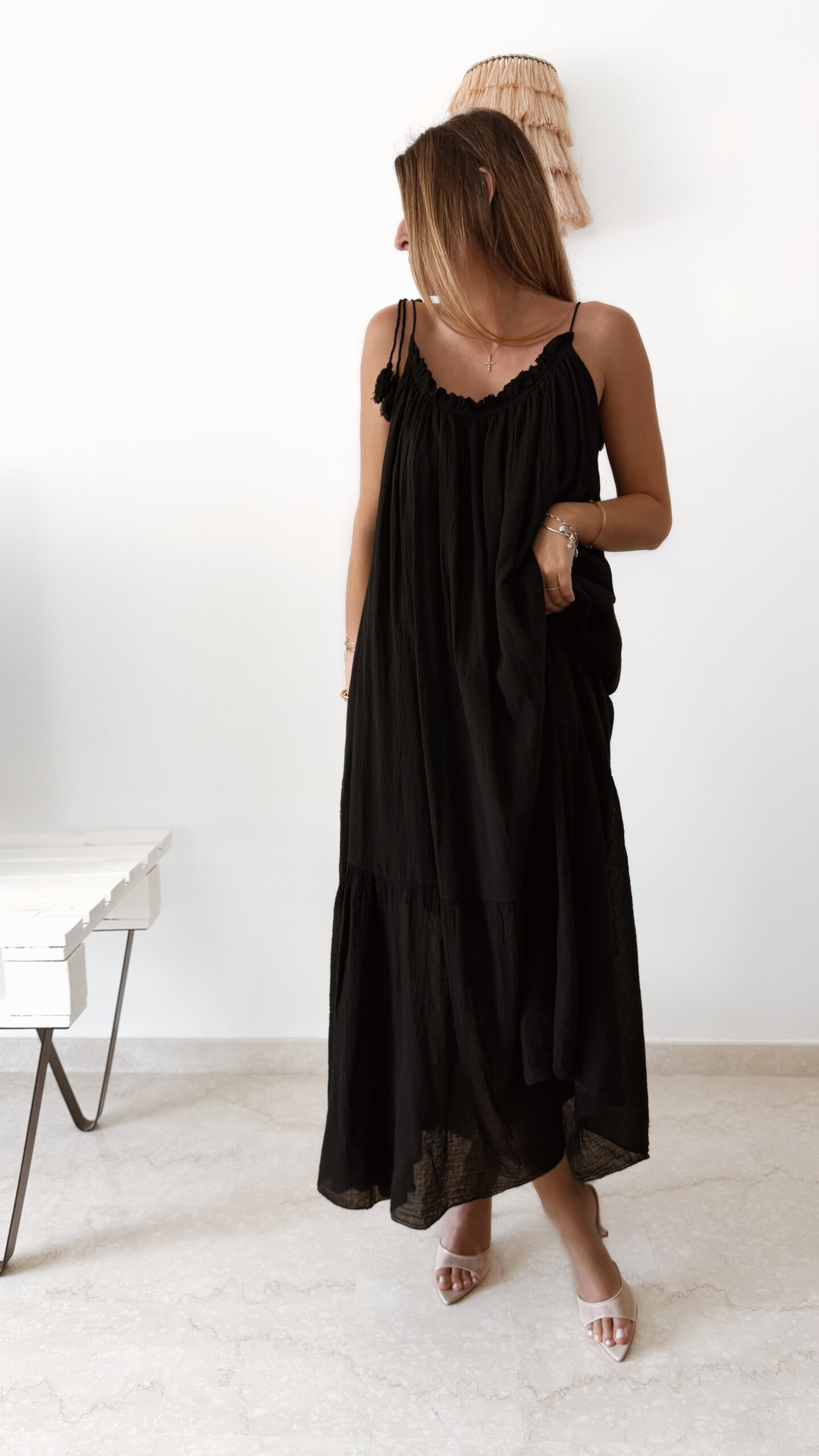 Robe longue noire à fines bretelles pour femme, coupe ample et fluide avec détails pompons, style bohème chic.