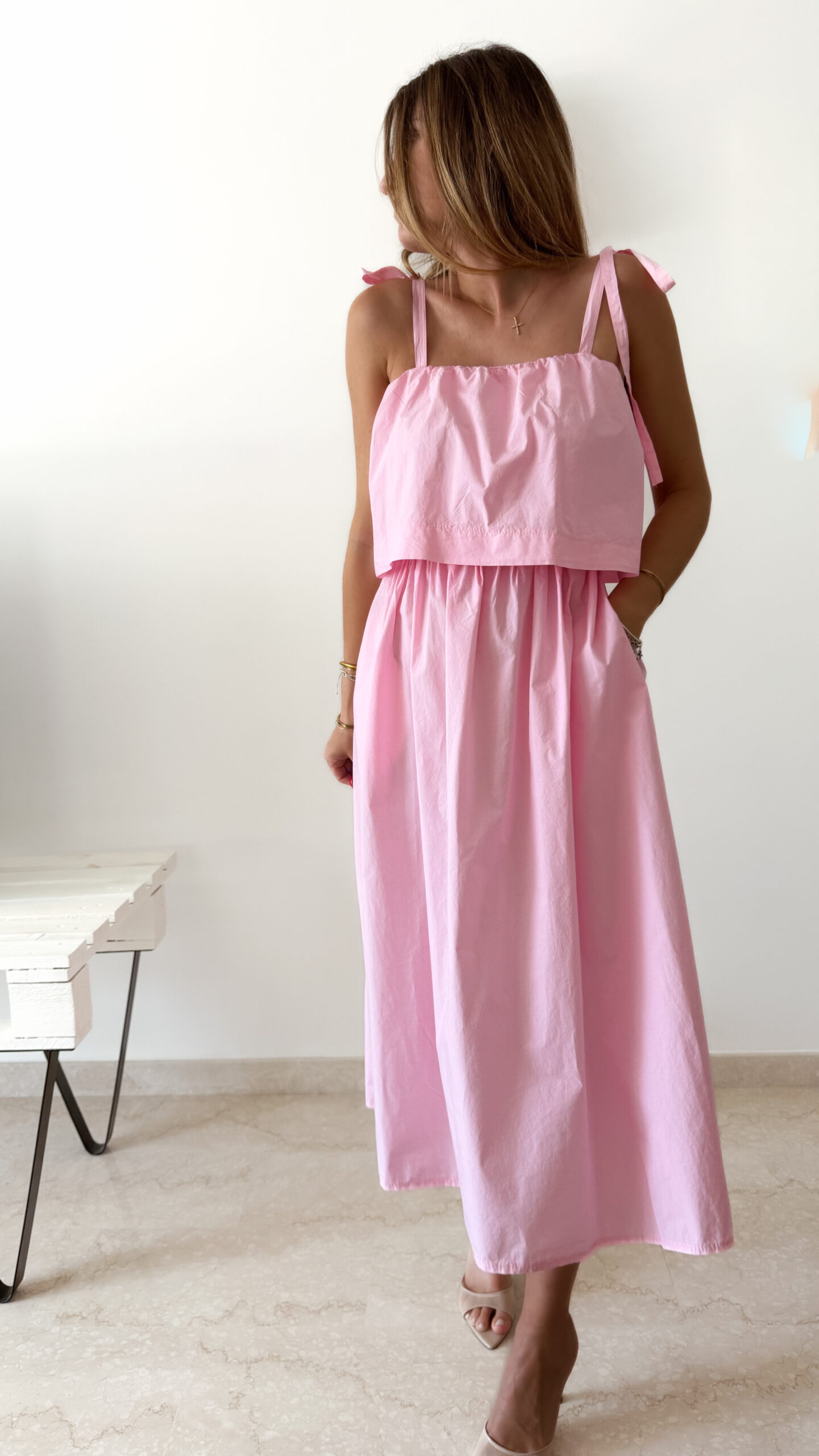 Robe midi rose poudré pour femme à bretelles nouées, coupe ample et fluide avec poches, style bohème chic et romantique.