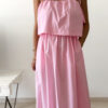 Robe midi rose poudré pour femme à bretelles nouées, coupe ample et fluide avec poches, style bohème chic et romantique.