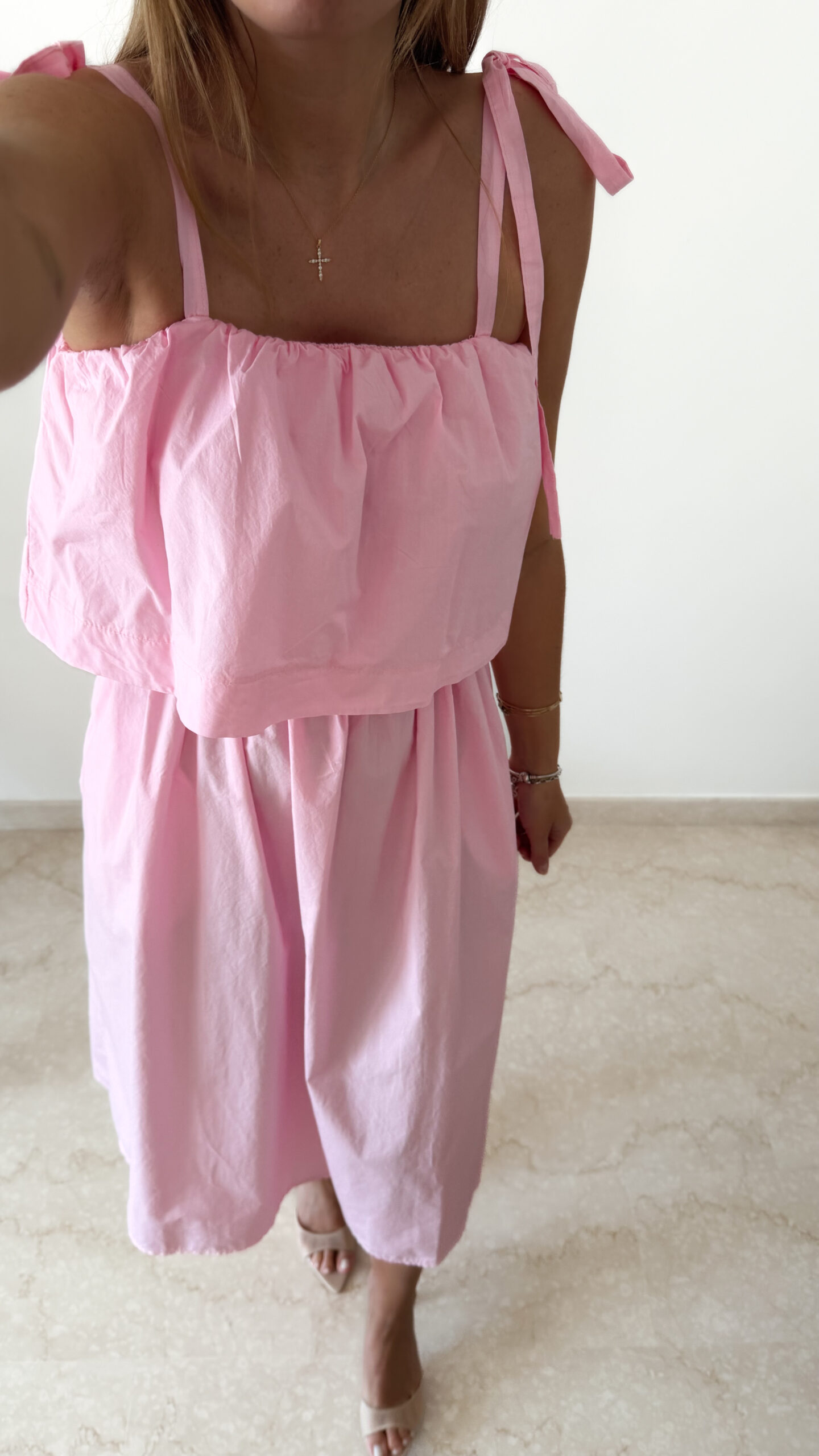 Robe midi rose poudré pour femme à bretelles nouées, coupe ample et fluide avec poches, style bohème chic et romantique.