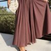 Ensemble bordeaux composé d'une blouse fluide à manches courtes et d'une jupe longue évasée, porté avec une pochette en crochet écru.