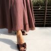 Ensemble bordeaux composé d'une blouse fluide à manches courtes et d'une jupe longue évasée, porté avec une pochette en crochet écru.