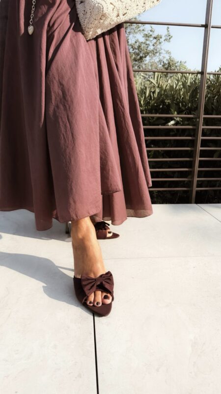 Ensemble bordeaux composé d'une blouse fluide à manches courtes et d'une jupe longue évasée, porté avec une pochette en crochet écru.