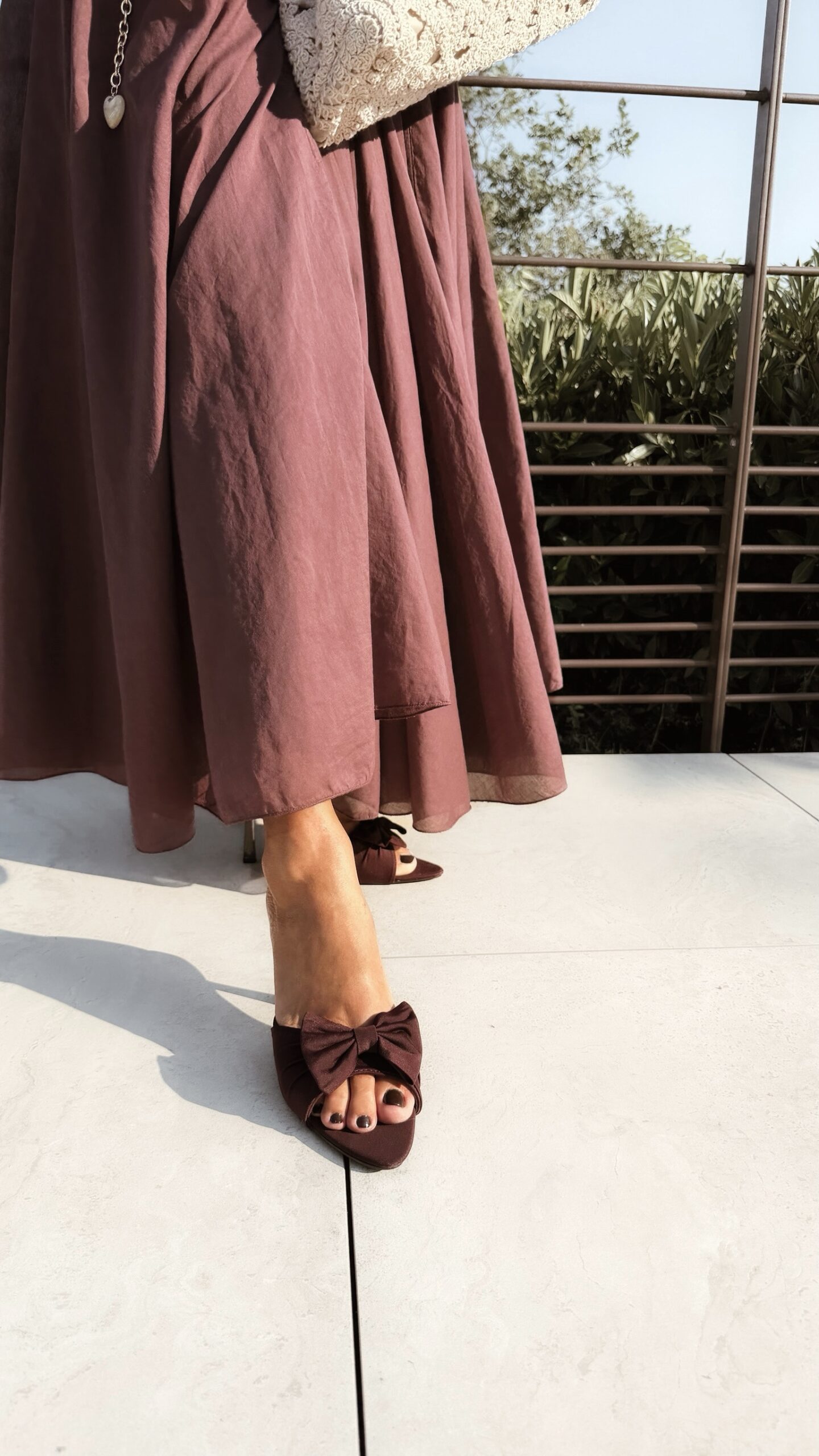 Ensemble bordeaux composé d'une blouse fluide à manches courtes et d'une jupe longue évasée, porté avec une pochette en crochet écru.