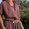 Ensemble bordeaux composé d'une blouse fluide à manches courtes et d'une jupe longue évasée, porté avec une pochette en crochet écru.