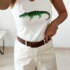 Débardeur femme blanc côtelé avec motif crocodile vert brodé en sequins, porté avec un pantalon écru taille haute pour un look estival tendance.
