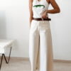 Débardeur femme blanc côtelé avec motif crocodile vert brodé en sequins, porté avec un pantalon écru taille haute pour un look estival tendance.