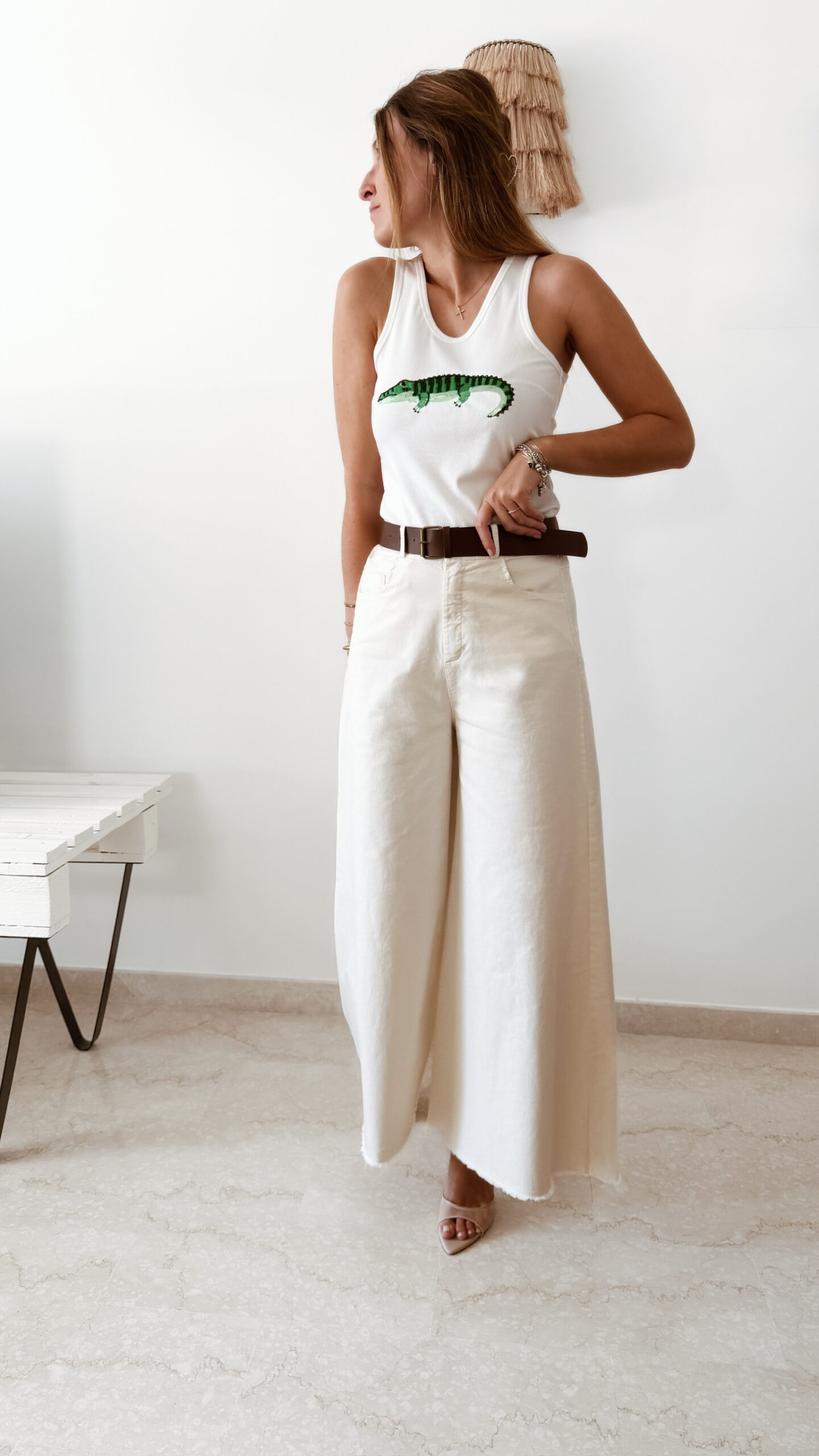 Débardeur femme blanc côtelé avec motif crocodile vert brodé en sequins, porté avec un pantalon écru taille haute pour un look estival tendance.