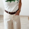 Débardeur femme blanc côtelé avec motif crocodile vert brodé en sequins, porté avec un pantalon écru taille haute pour un look estival tendance.