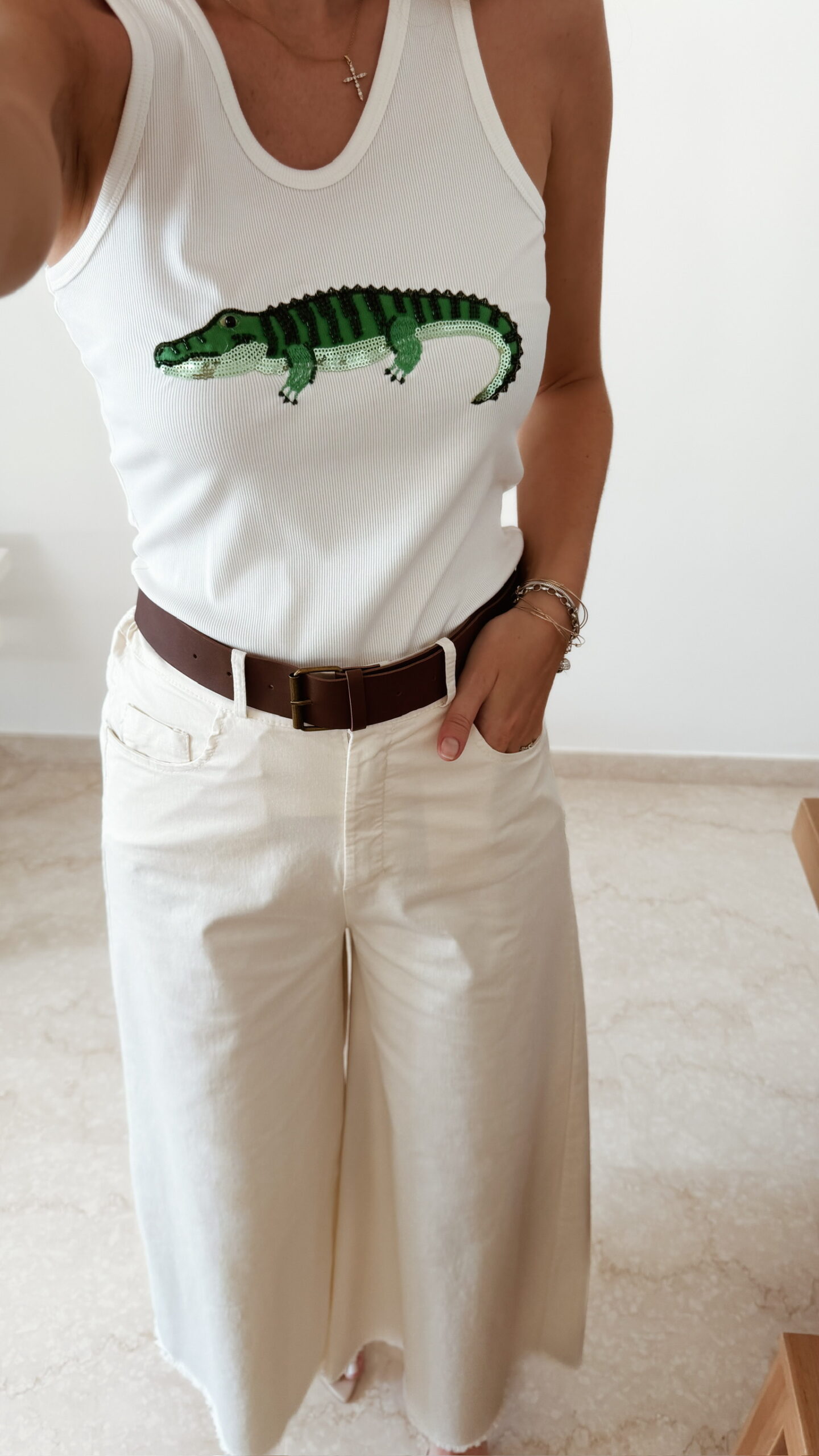 Débardeur femme blanc côtelé avec motif crocodile vert brodé en sequins, porté avec un pantalon écru taille haute pour un look estival tendance.