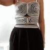 Ensemble femme noir composé d'un top texturé blanc et noir à bretelles et d'un pantalon fluide taille haute, style chic et élégant.