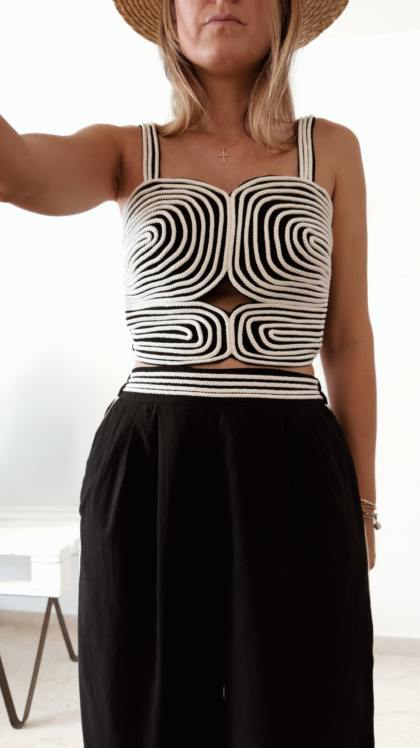 Ensemble femme noir composé d'un top texturé blanc et noir à bretelles et d'un pantalon fluide taille haute, style chic et élégant.