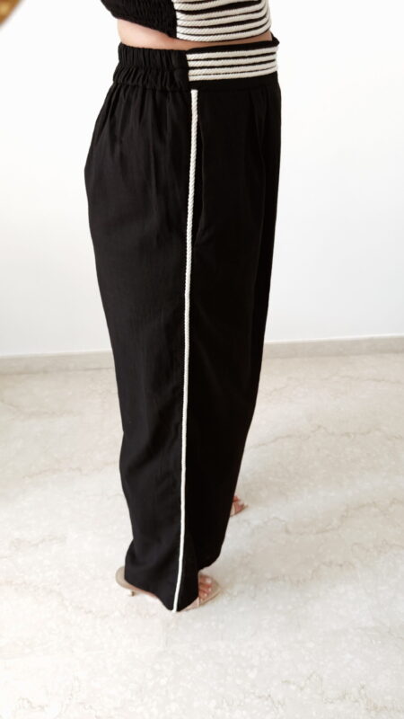 Ensemble femme noir composé d'un top texturé blanc et noir à bretelles et d'un pantalon fluide taille haute, style chic et élégant.