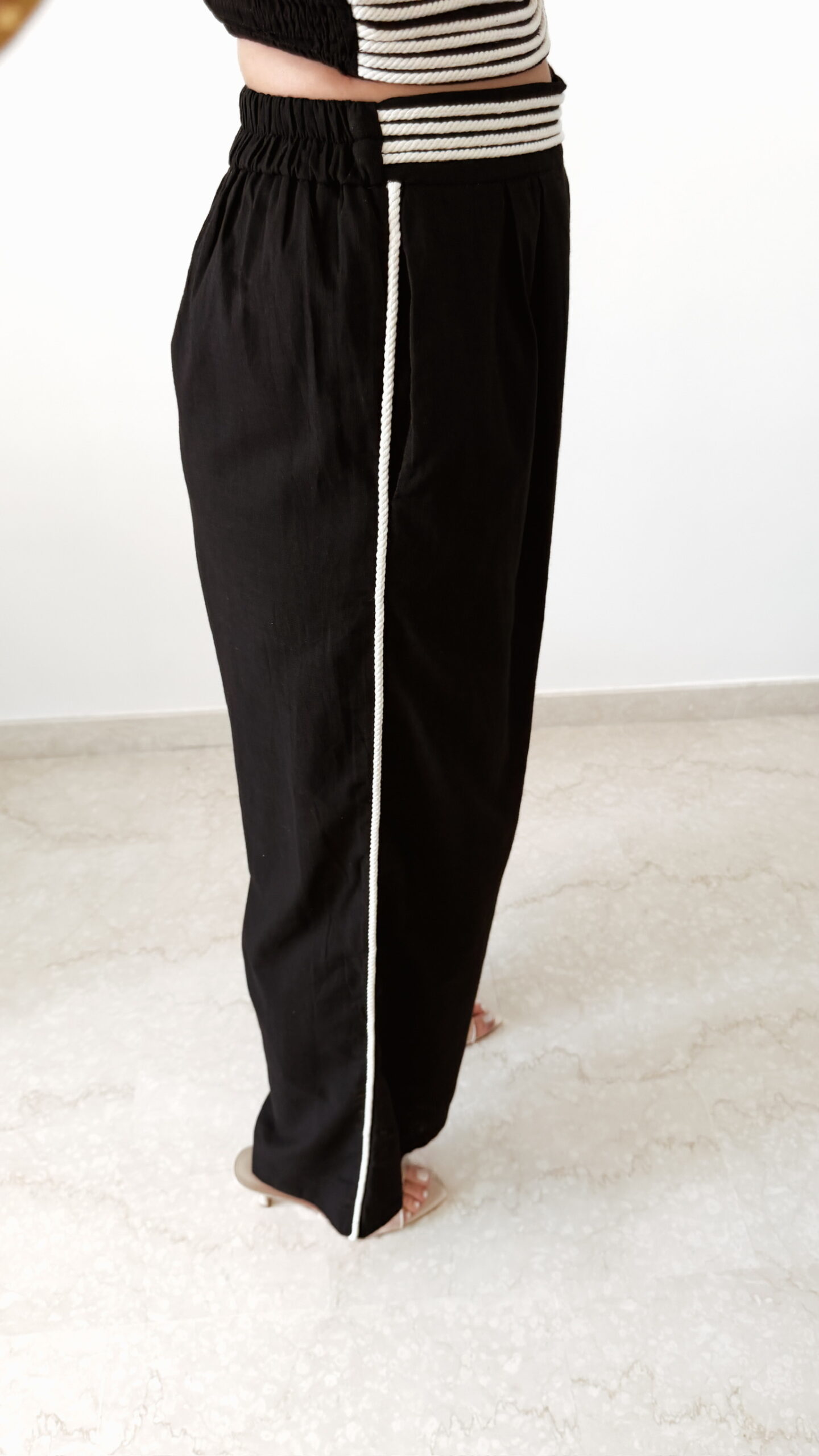 Ensemble femme noir composé d'un top texturé blanc et noir à bretelles et d'un pantalon fluide taille haute, style chic et élégant.