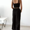 Ensemble femme noir composé d'un top texturé blanc et noir à bretelles et d'un pantalon fluide taille haute, style chic et élégant.