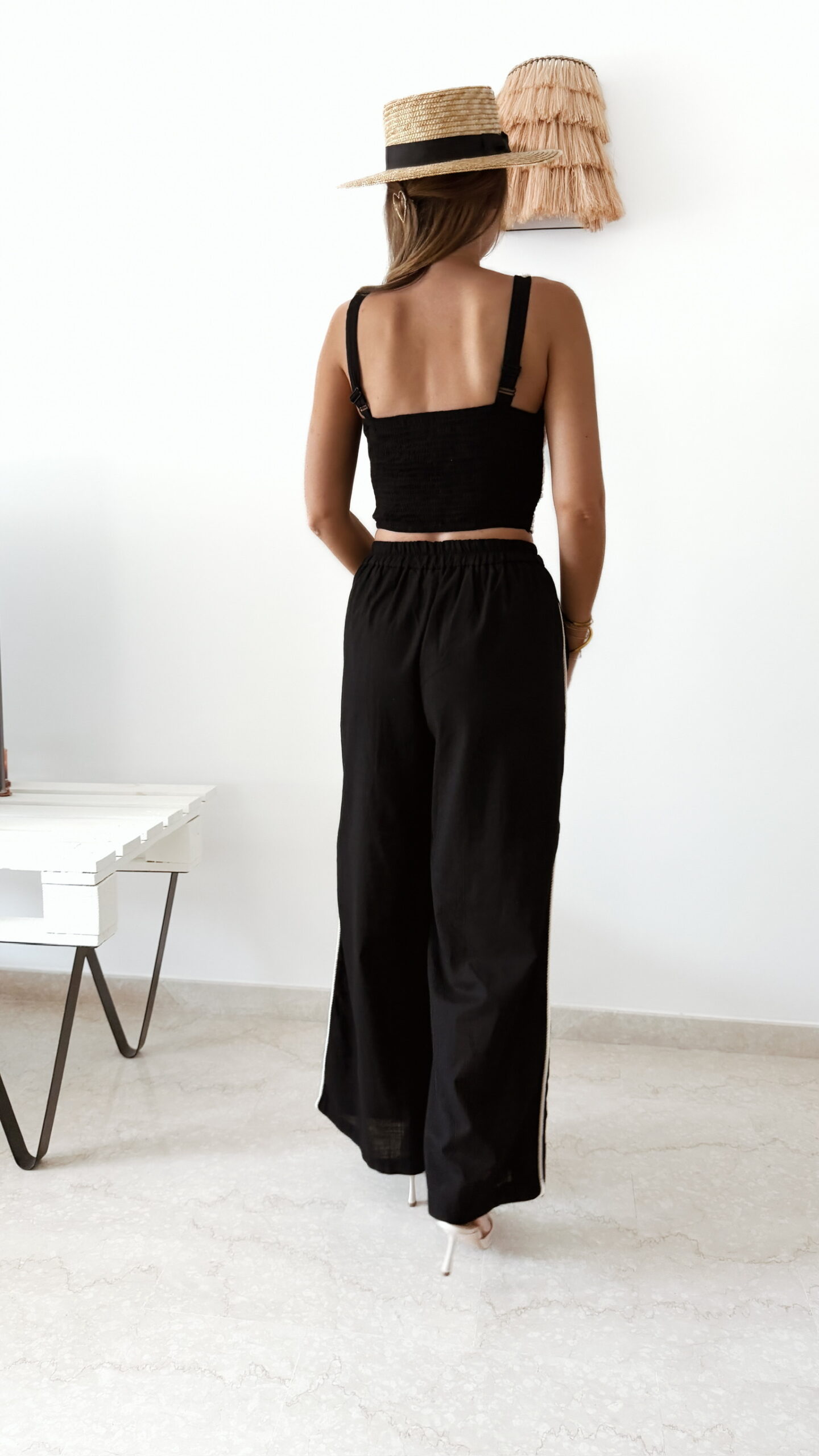 Ensemble femme noir composé d'un top texturé blanc et noir à bretelles et d'un pantalon fluide taille haute, style chic et élégant.