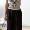 Ensemble femme noir composé d'un top texturé blanc et noir à bretelles et d'un pantalon fluide taille haute, style chic et élégant.