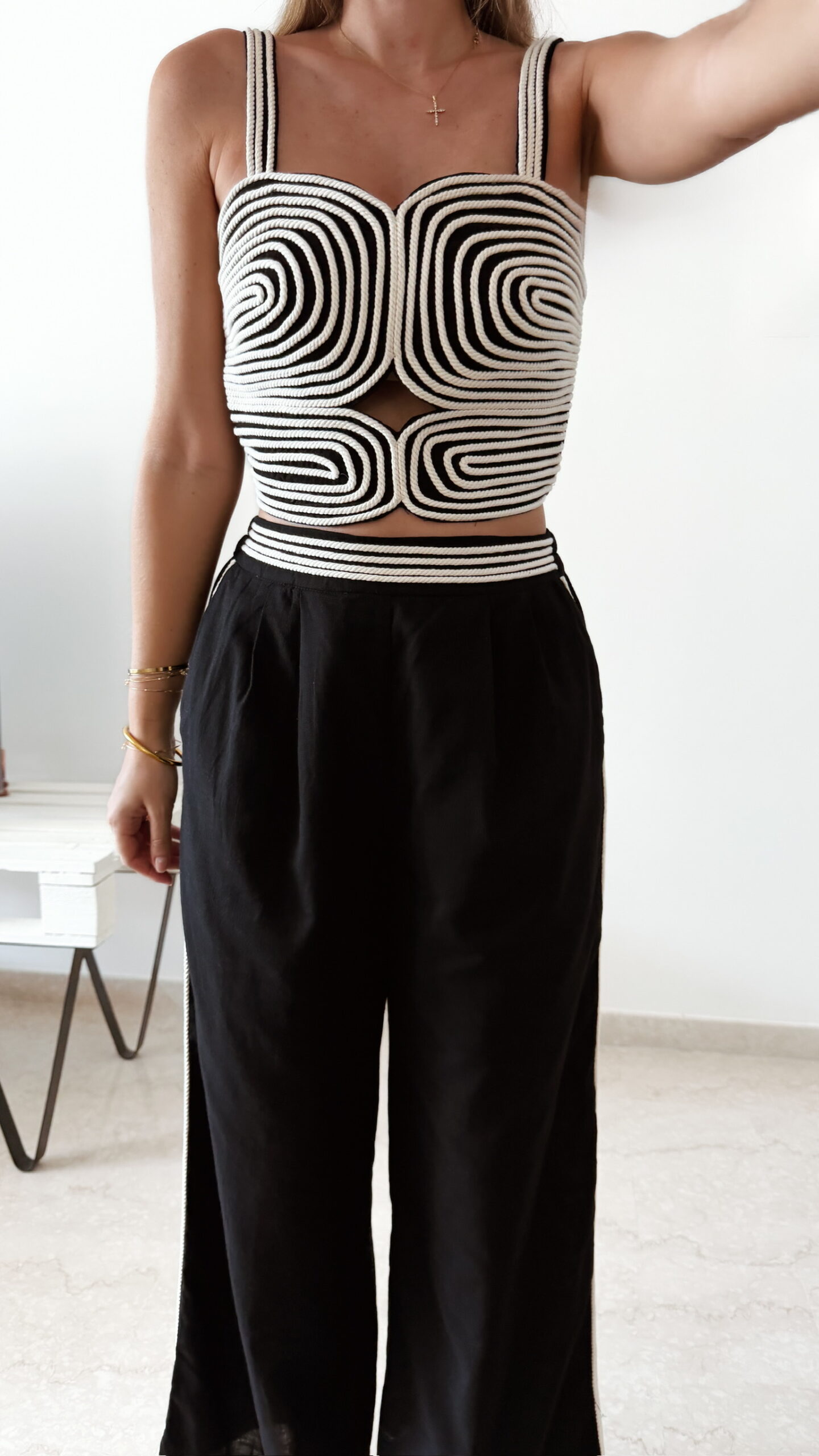 Ensemble femme noir composé d'un top texturé blanc et noir à bretelles et d'un pantalon fluide taille haute, style chic et élégant.