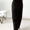 Ensemble femme noir composé d'un top texturé blanc et noir à bretelles et d'un pantalon fluide taille haute, style chic et élégant.