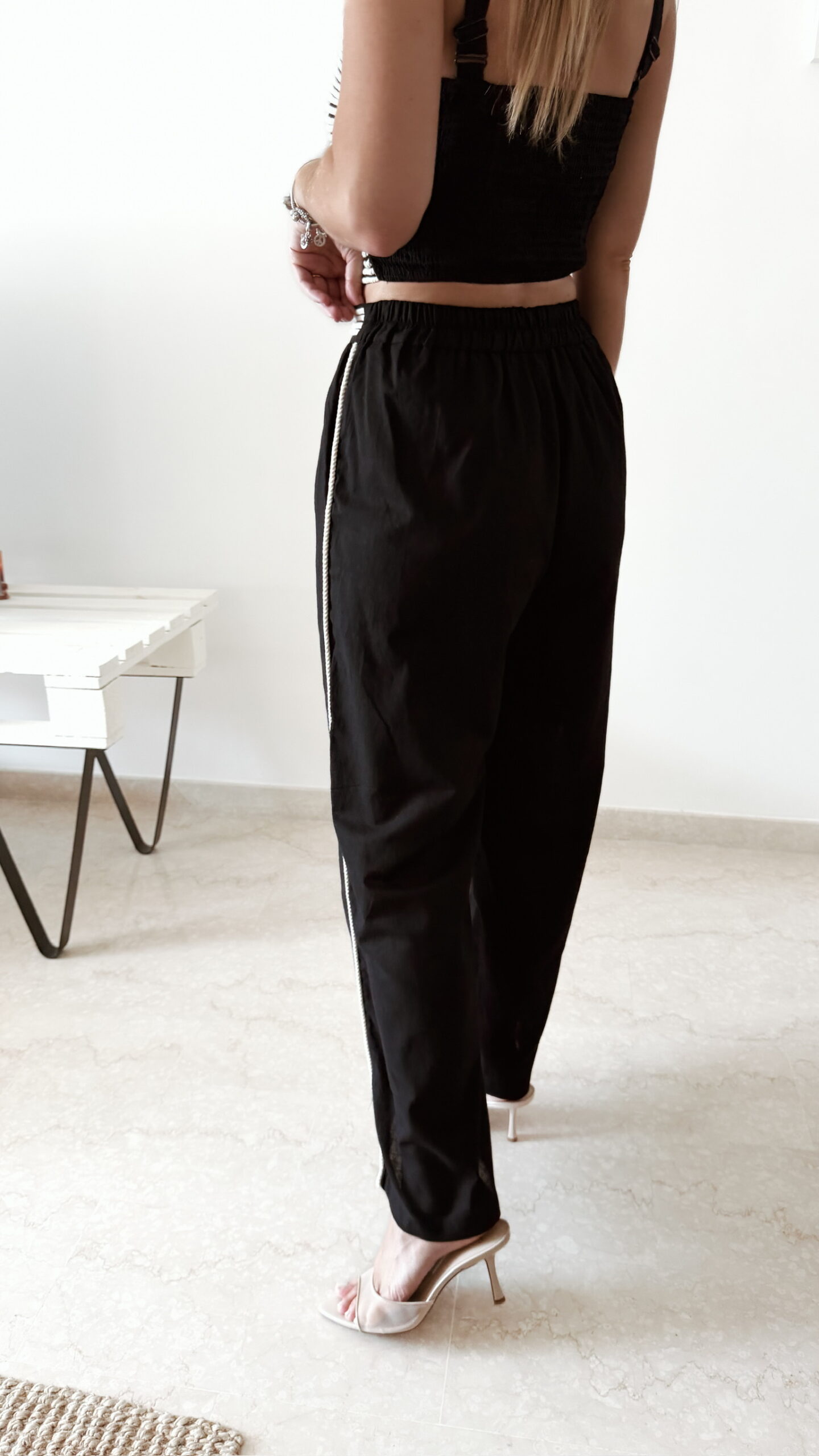 Ensemble femme noir composé d'un top texturé blanc et noir à bretelles et d'un pantalon fluide taille haute, style chic et élégant.