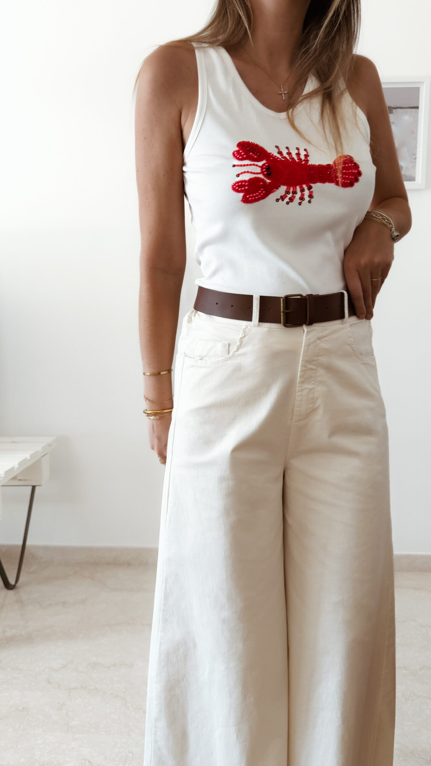 Pantalon femme écru taille haute coupe large avec débardeur blanc imprimé homard rouge, tenue estivale chic et décontractée.