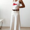 Pantalon femme écru taille haute coupe large avec débardeur blanc imprimé homard rouge, tenue estivale chic et décontractée.