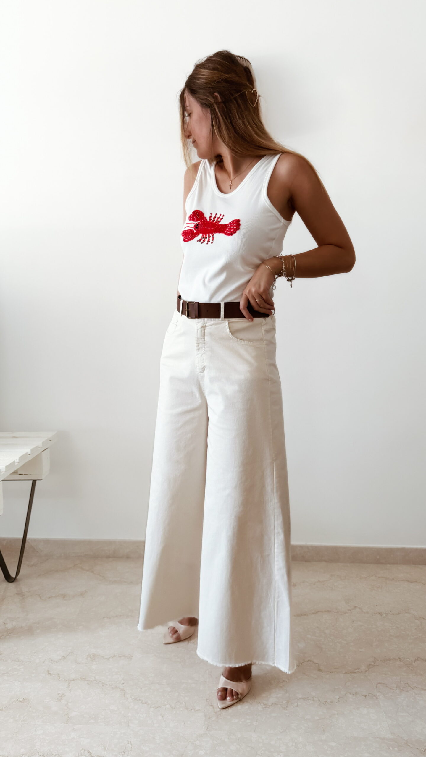 Pantalon femme écru taille haute coupe large avec débardeur blanc imprimé homard rouge, tenue estivale chic et décontractée.