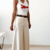 Pantalon femme écru taille haute coupe large avec débardeur blanc imprimé homard rouge, tenue estivale chic et décontractée.
