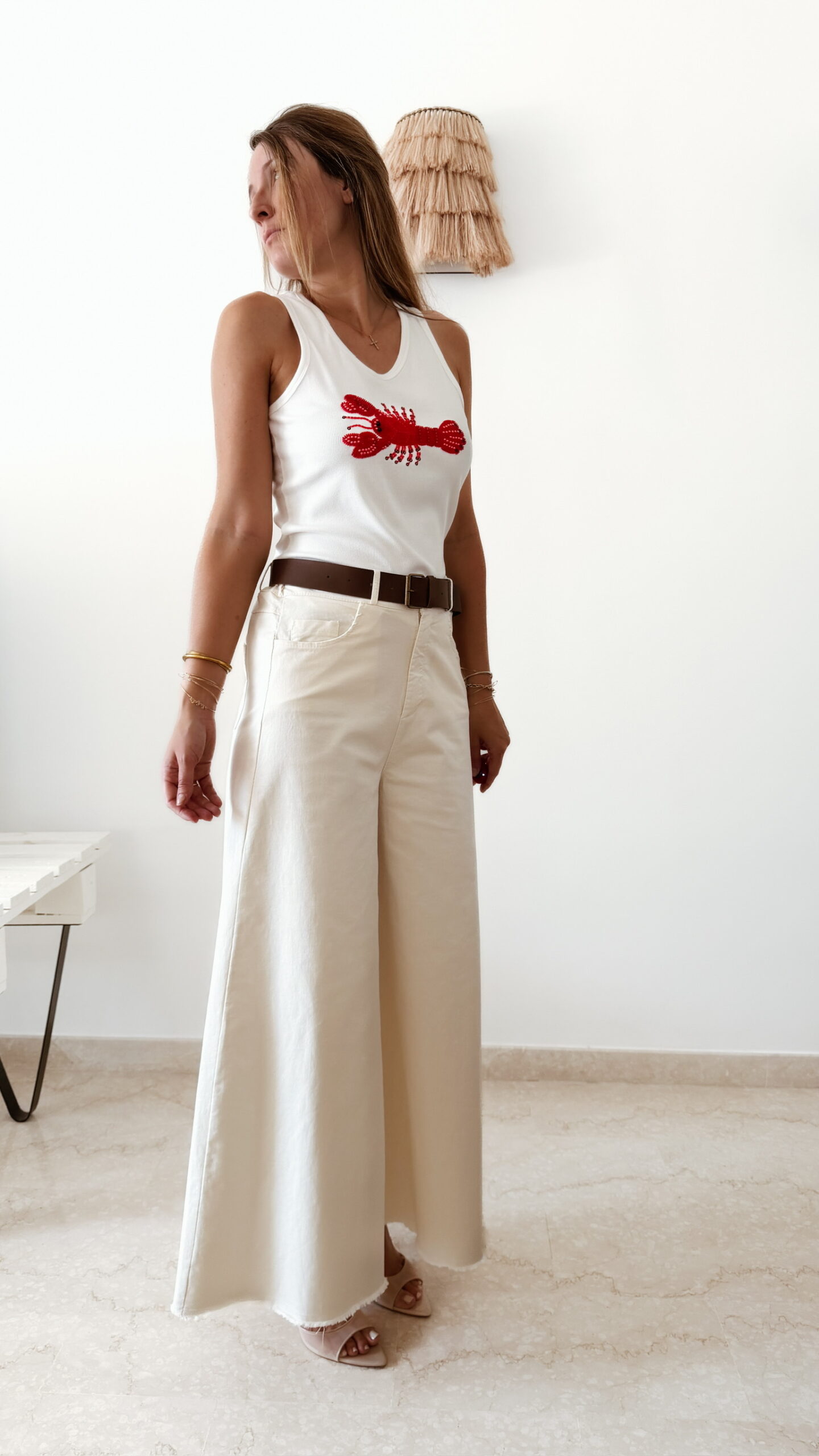 Pantalon femme écru taille haute coupe large avec débardeur blanc imprimé homard rouge, tenue estivale chic et décontractée.