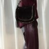 Sac noir femme à franges avec clous dorés, porté à l’épaule, style bohème chic
