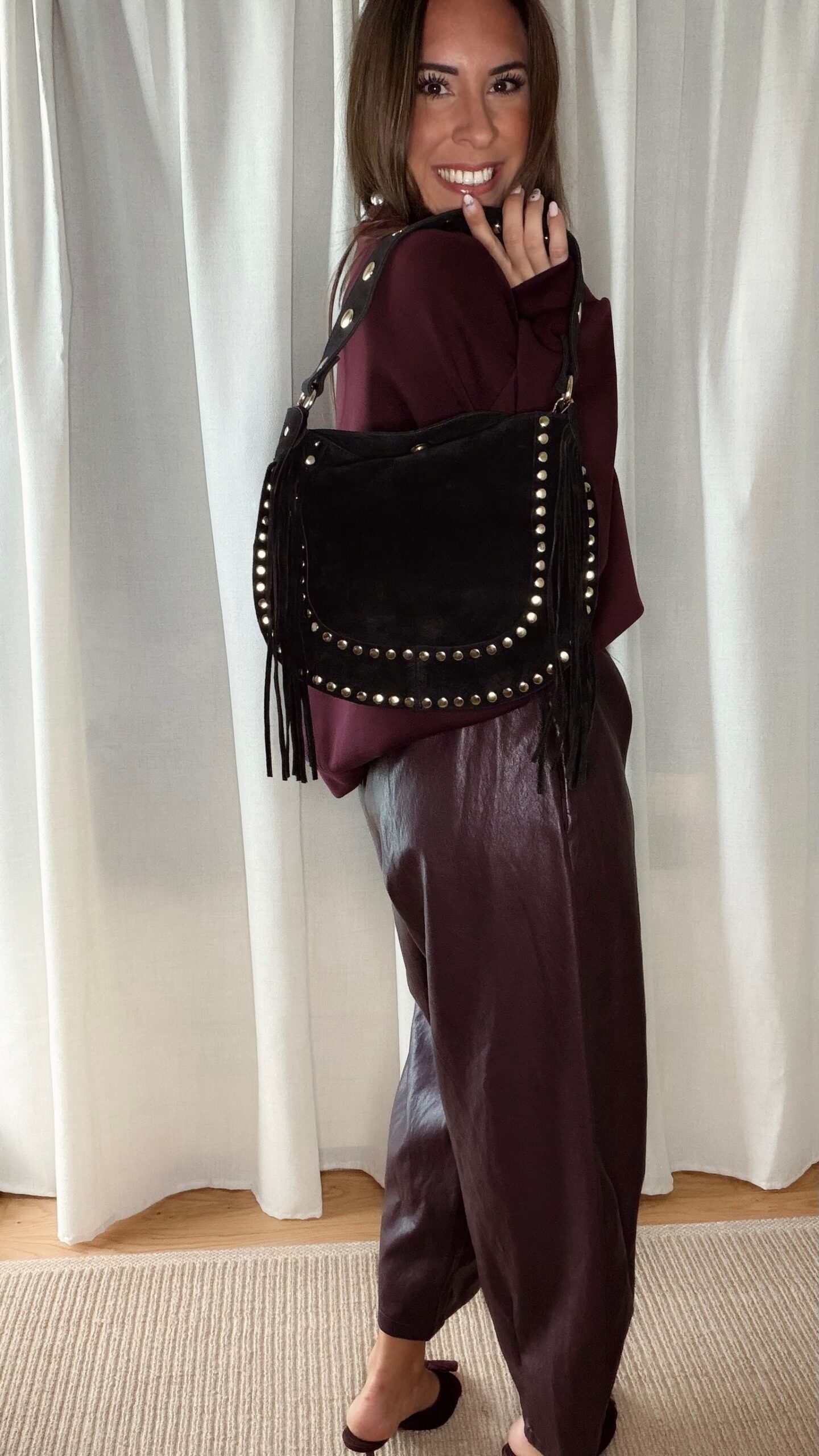 Sac noir femme à franges avec clous dorés, porté à l’épaule, style bohème chic