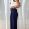 Pantalon bleu femme coupe large et fluide, porté avec un débardeur blanc, style chic et élégant