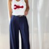 Pantalon bleu femme coupe large et fluide, porté avec un débardeur blanc, style chic et élégant