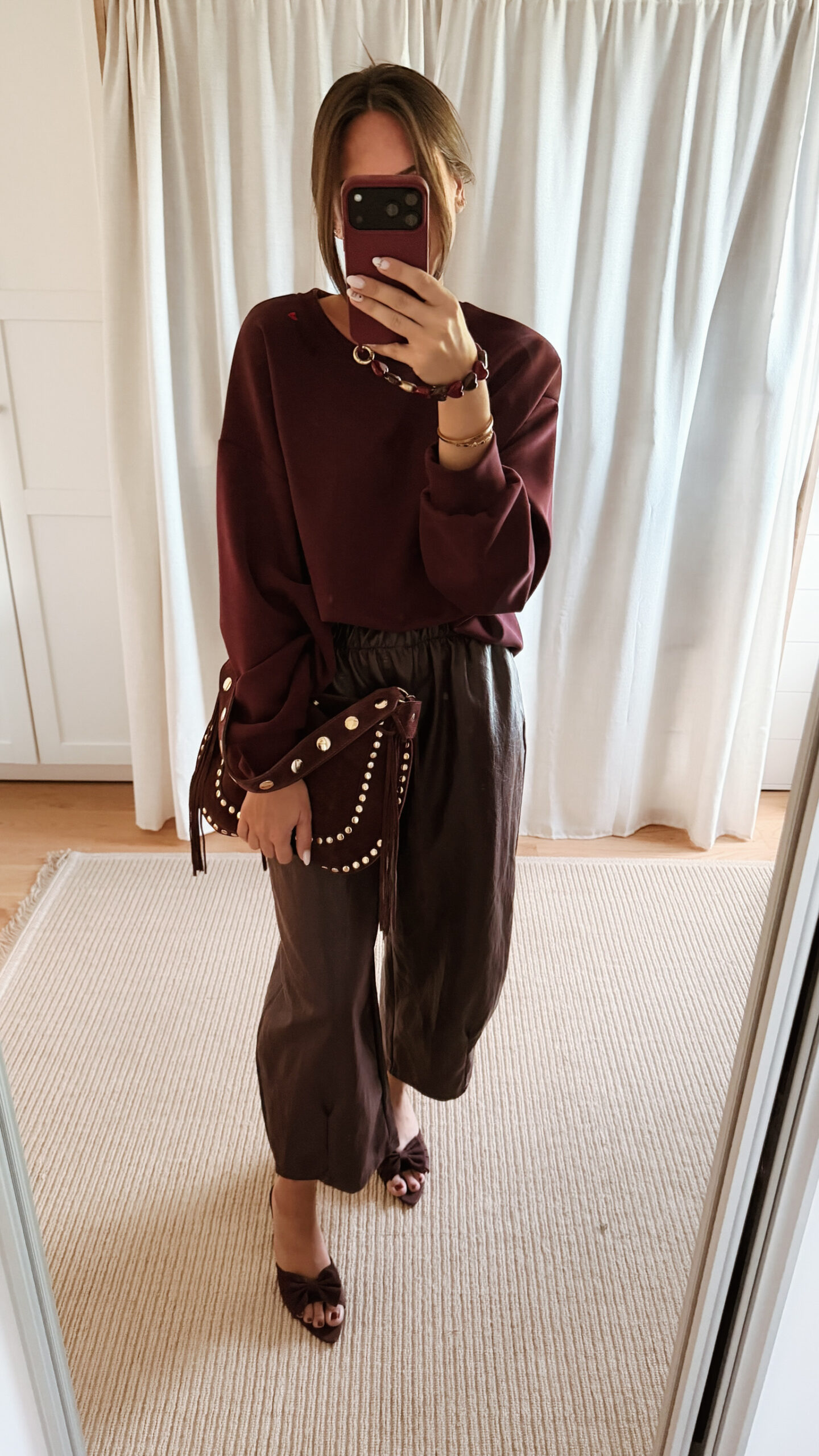 Sac bordeaux femme à franges avec clous dorés, porté à l’épaule, style bohème chic