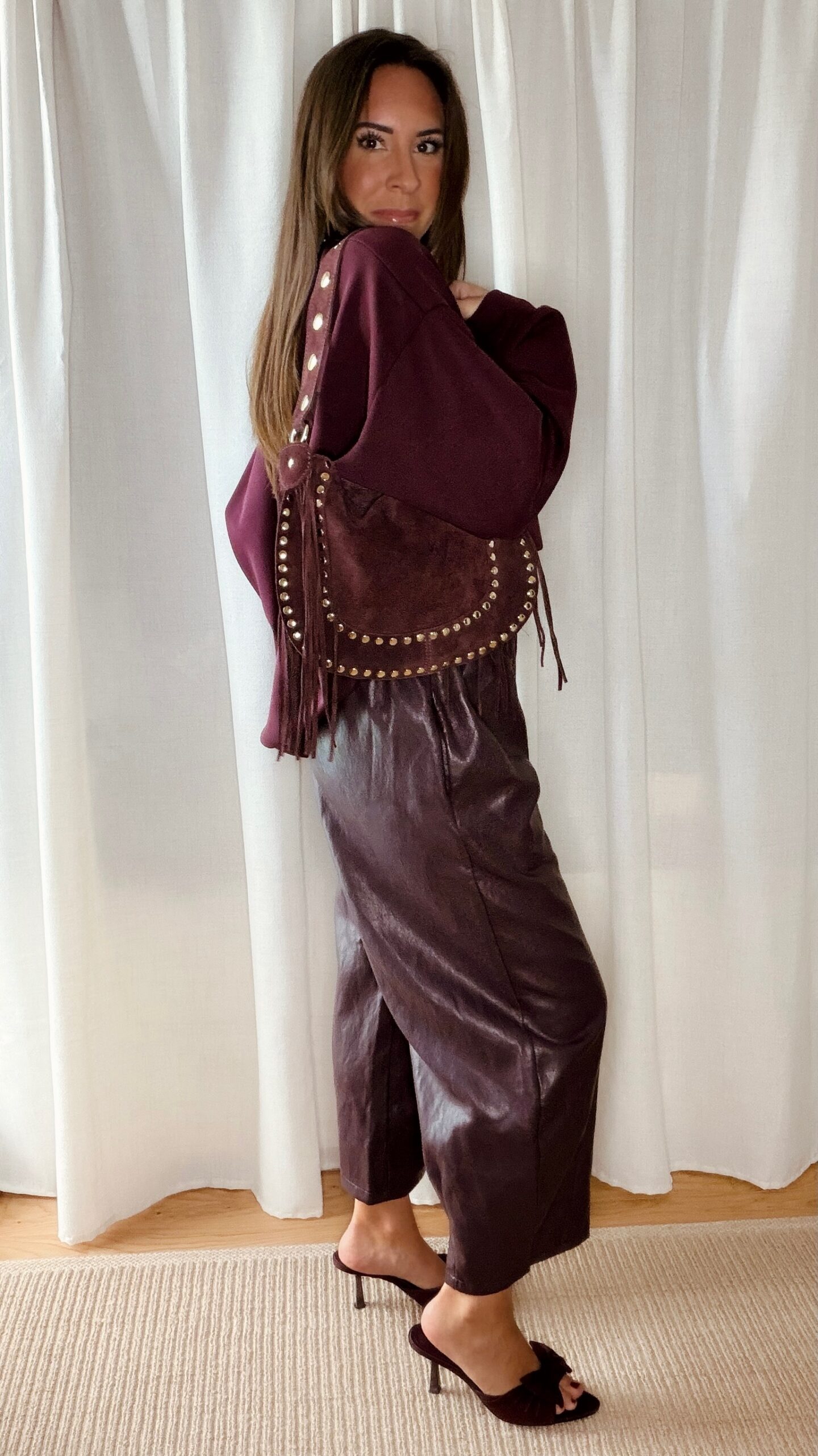 Sac bordeaux femme à franges avec clous dorés, porté à l’épaule, style bohème chic