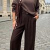 Femme portant un sweat bordeaux et un pantalon large en simili cuir bordeaux avec sac à main bordeaux clouté à franges