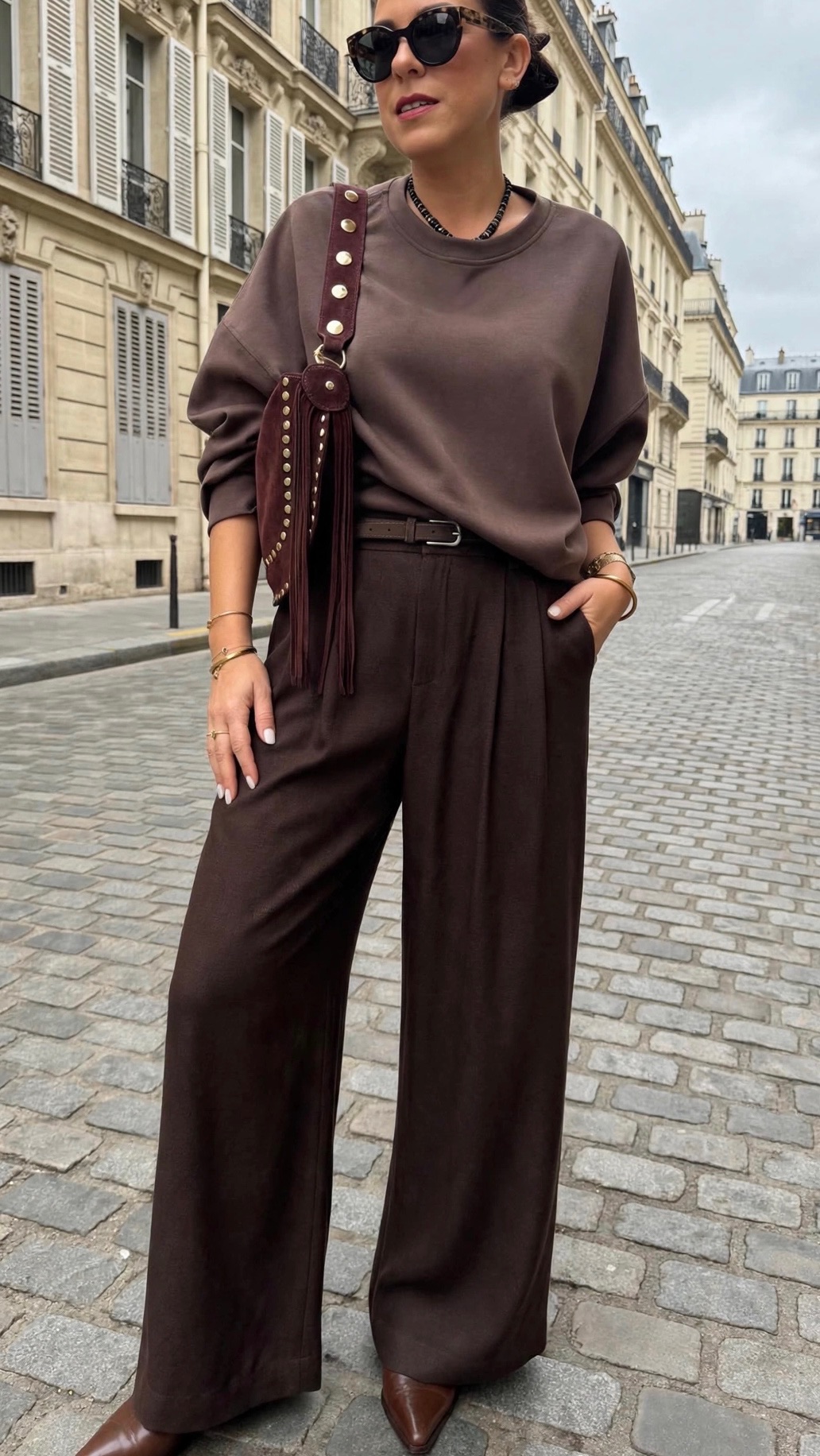 Femme portant un sweat bordeaux et un pantalon large en simili cuir bordeaux avec sac à main bordeaux clouté à franges