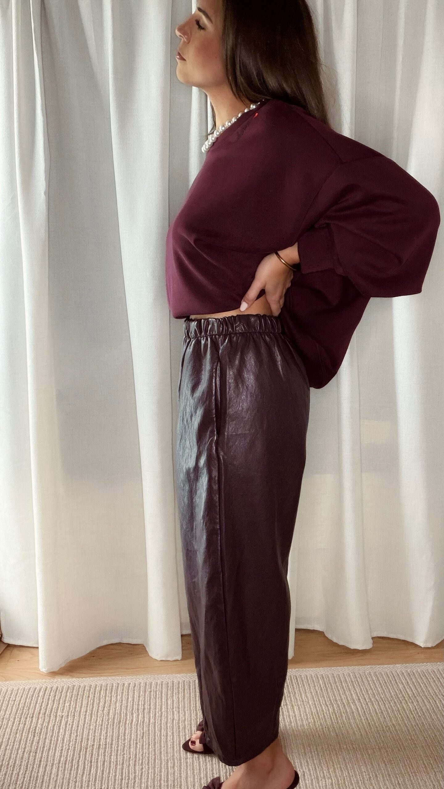 Sweat bordeaux femme porté avec un pantalon marron fluide et un sac à franges, tenue chic et tendance