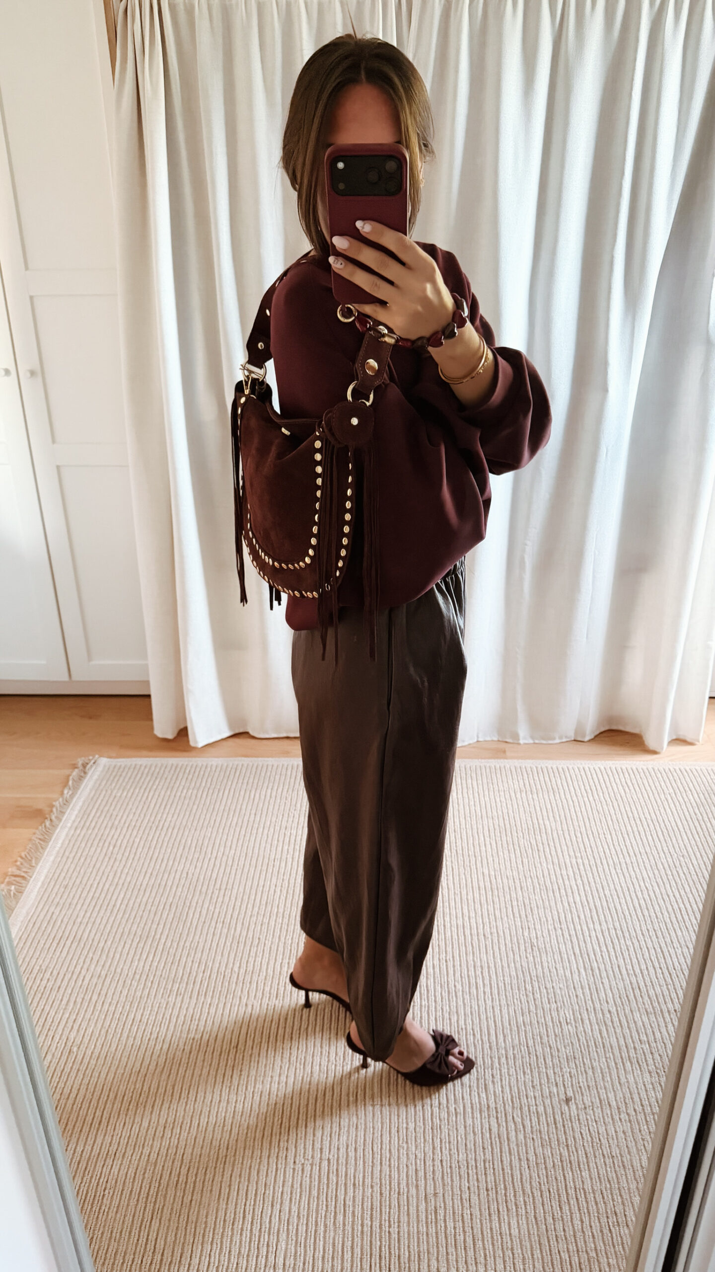 Sac bordeaux femme à franges avec clous dorés, porté à l’épaule, style bohème chic