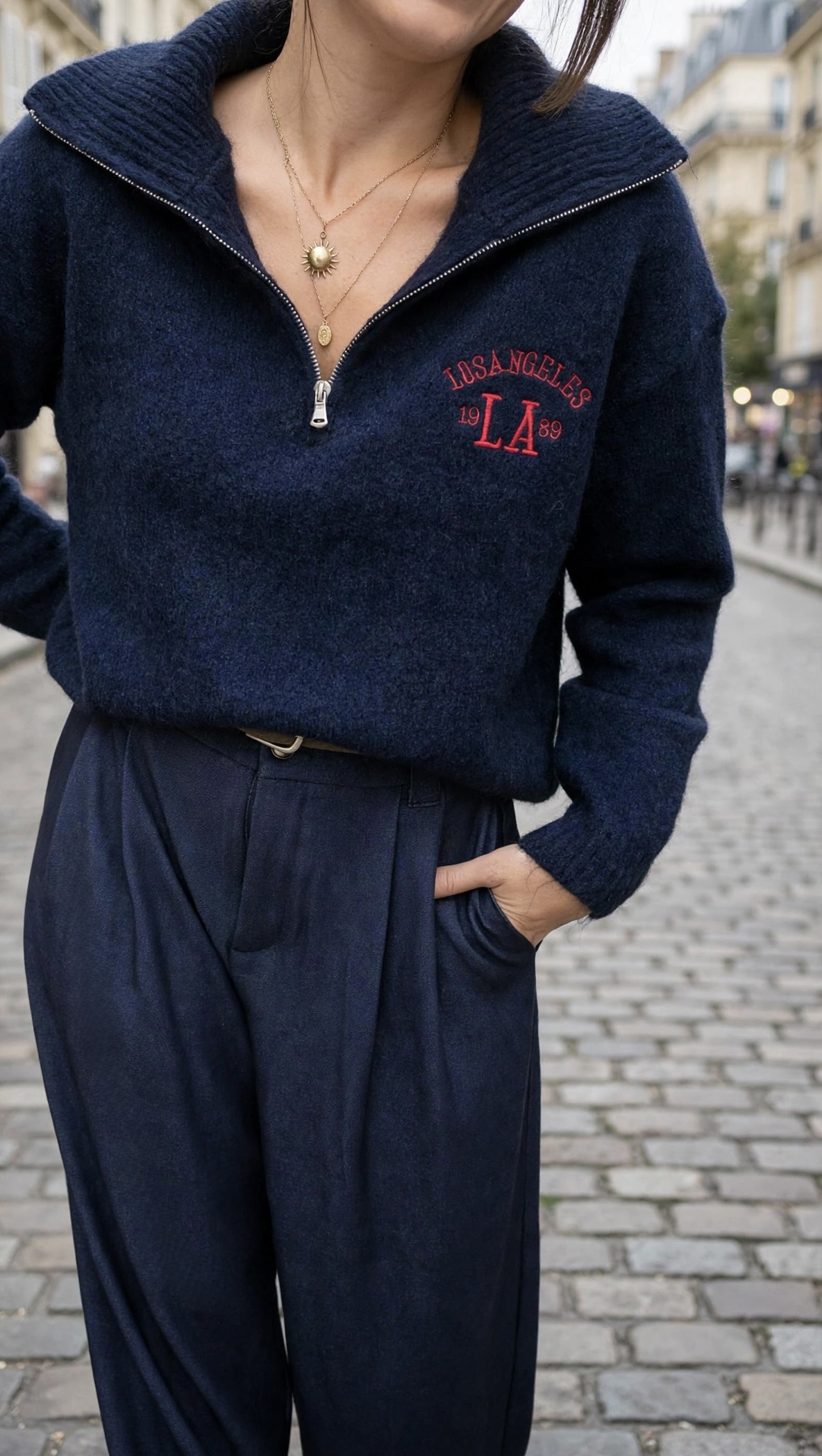 Pull femme bleu marine Los Angeles avec col montant zippé et inscription rouge sur la poitrine, associé à un pantalon large bleu marine à pinces.