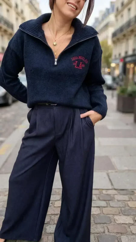 Pull femme bleu marine Los Angeles à col montant zippé avec inscription rouge sur la poitrine, porté avec un pantalon large bleu marine.